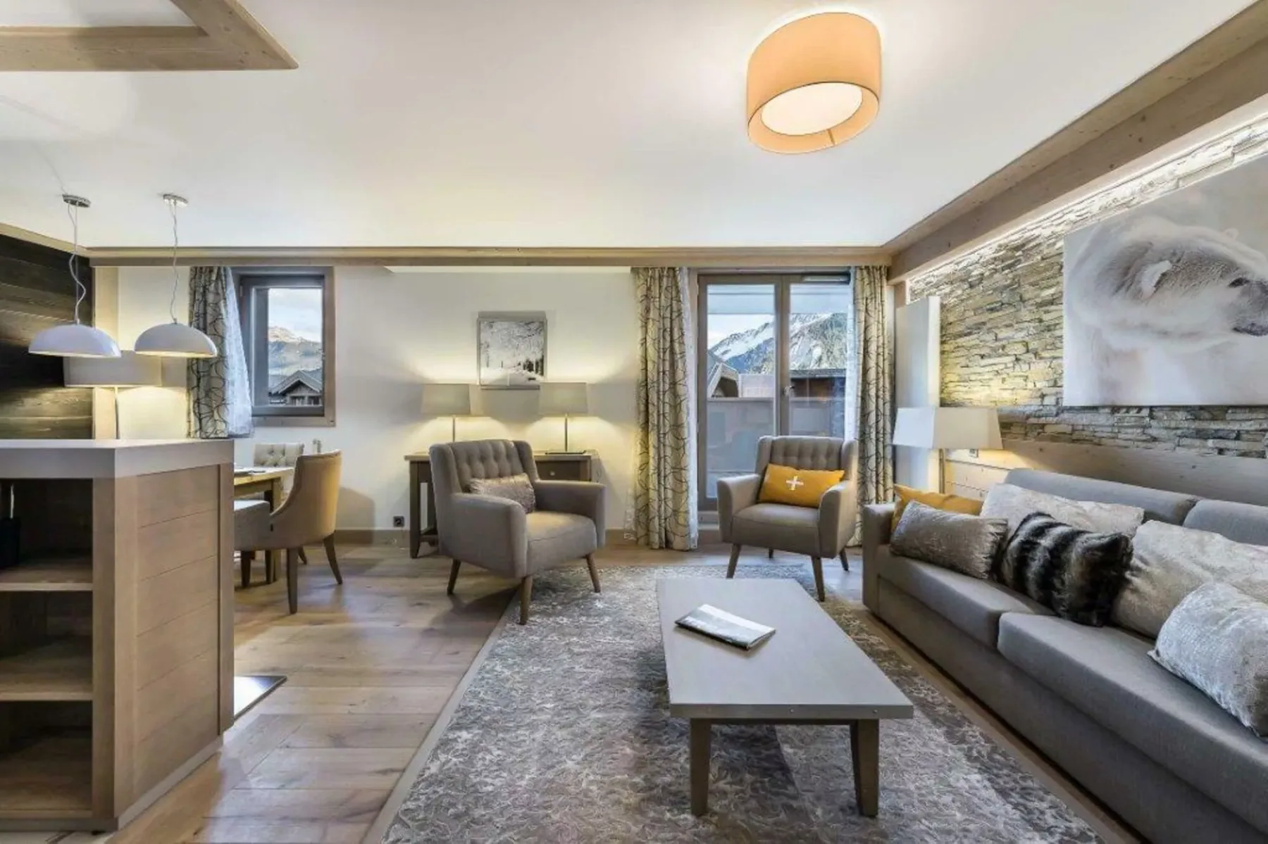 A living room with seating around a coffee table and large windows.