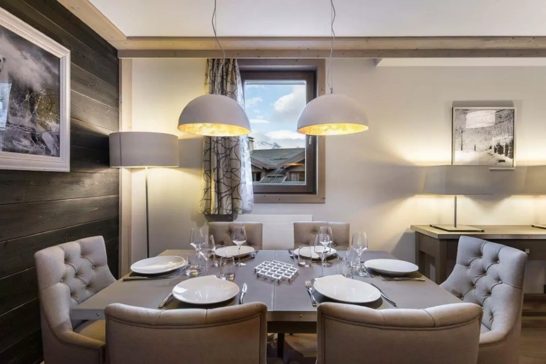 A dining area with a set table beneath two pendant lights.