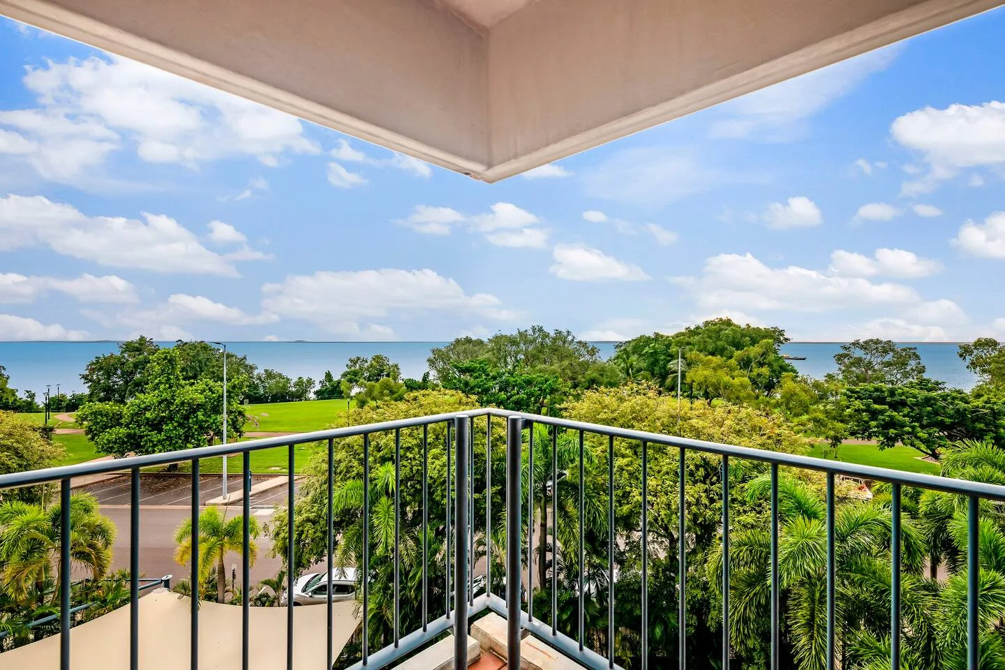 A balcony overlooks green treetops and a distant strip of water.