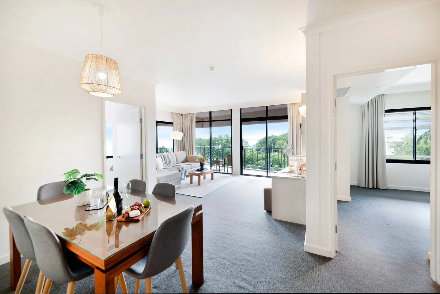 An open-plan living and dining area has large windows and a dining table.