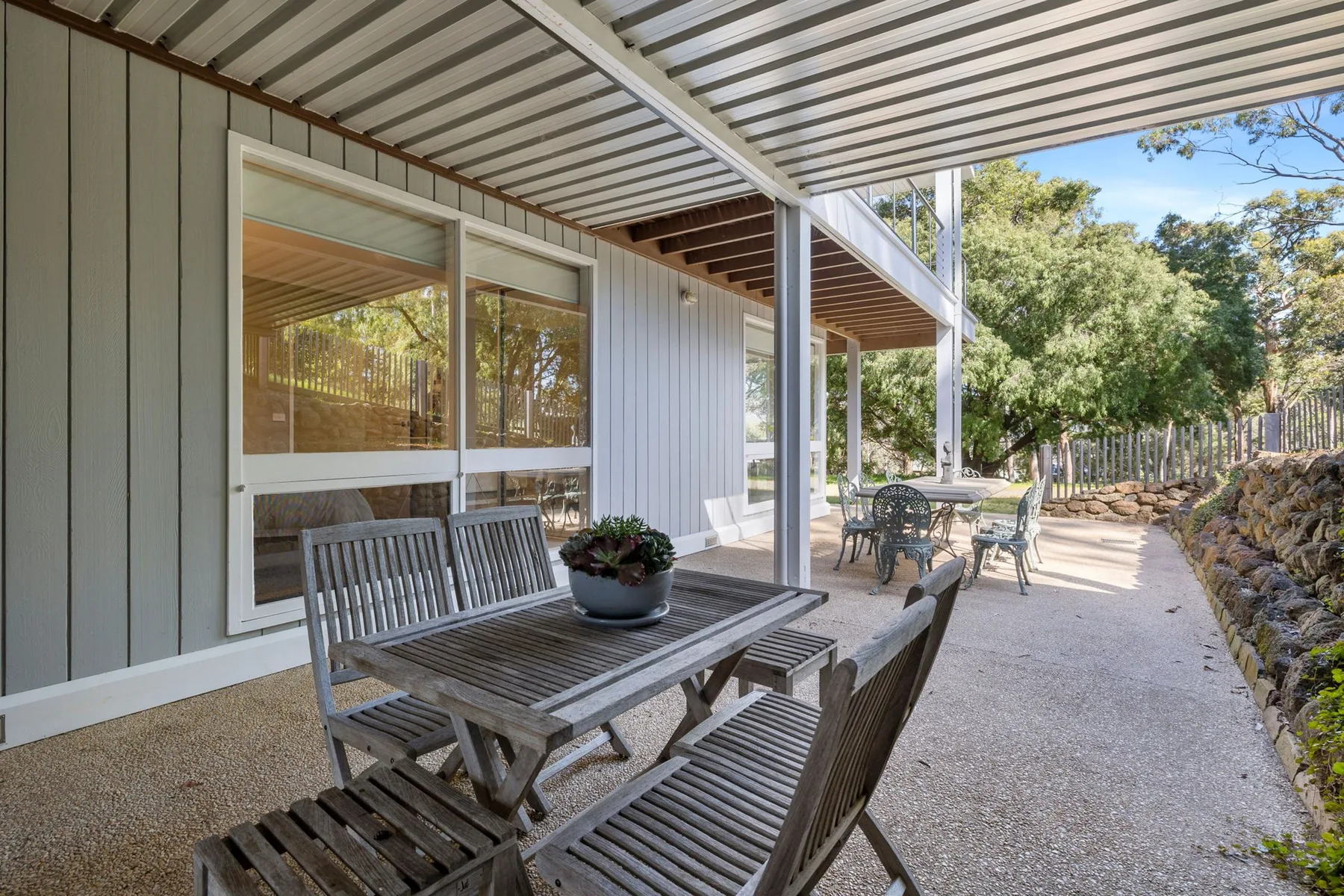 A covered outdoor patio with a wooden dining table and seating.