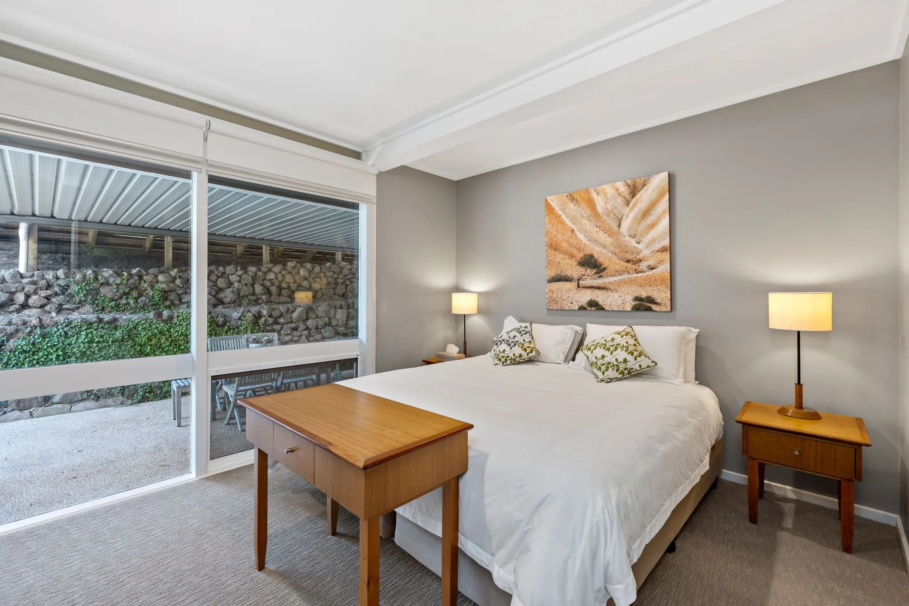 A bedroom with a bed, bedside tables, and sliding glass doors.