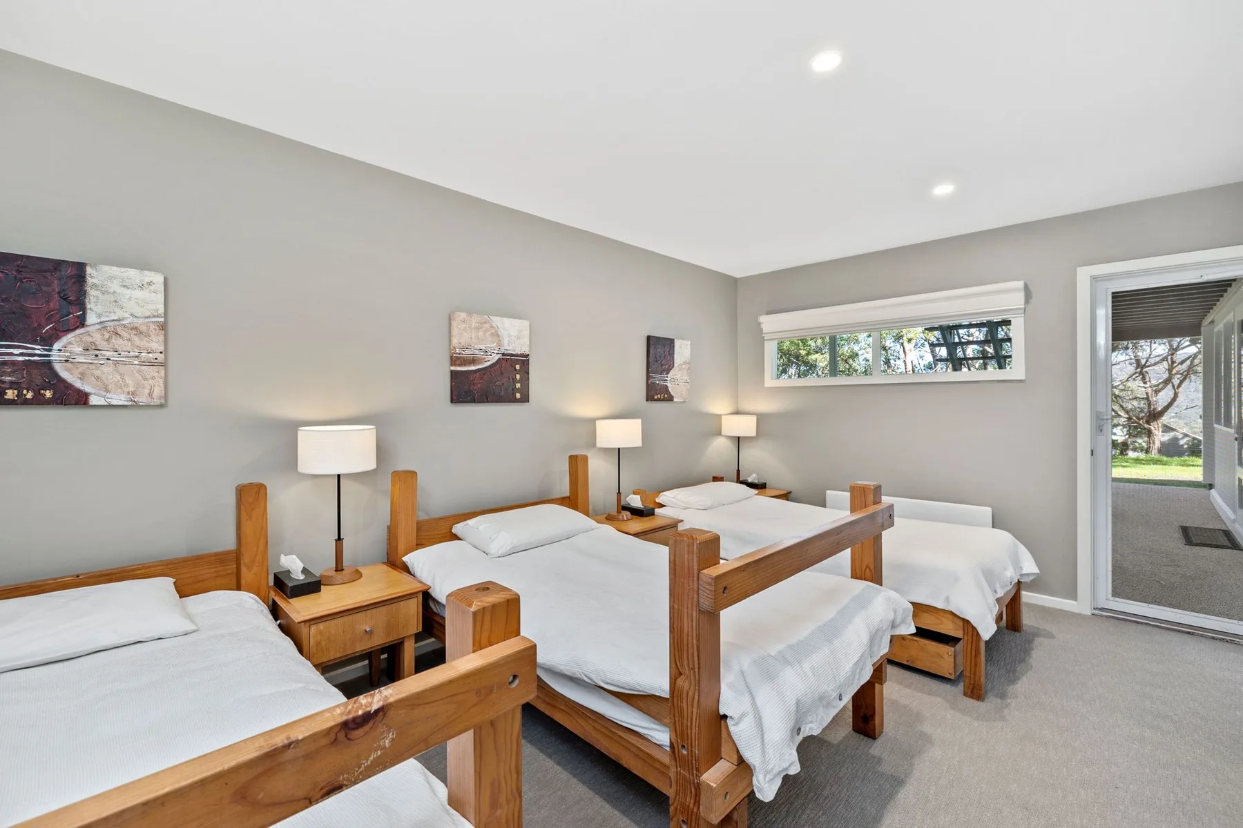A bedroom with several wooden beds and white bedding.