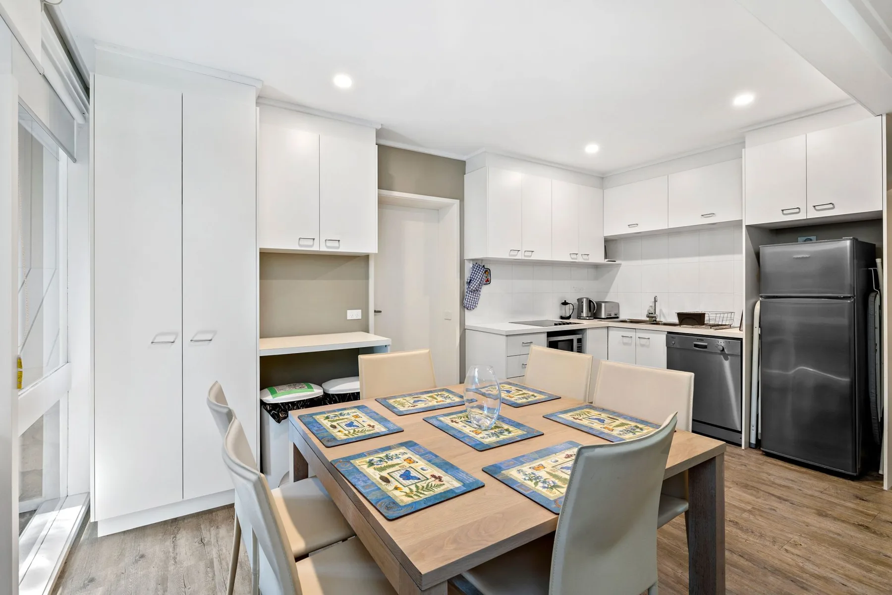A bright kitchen and dining area with a table set with placemats.