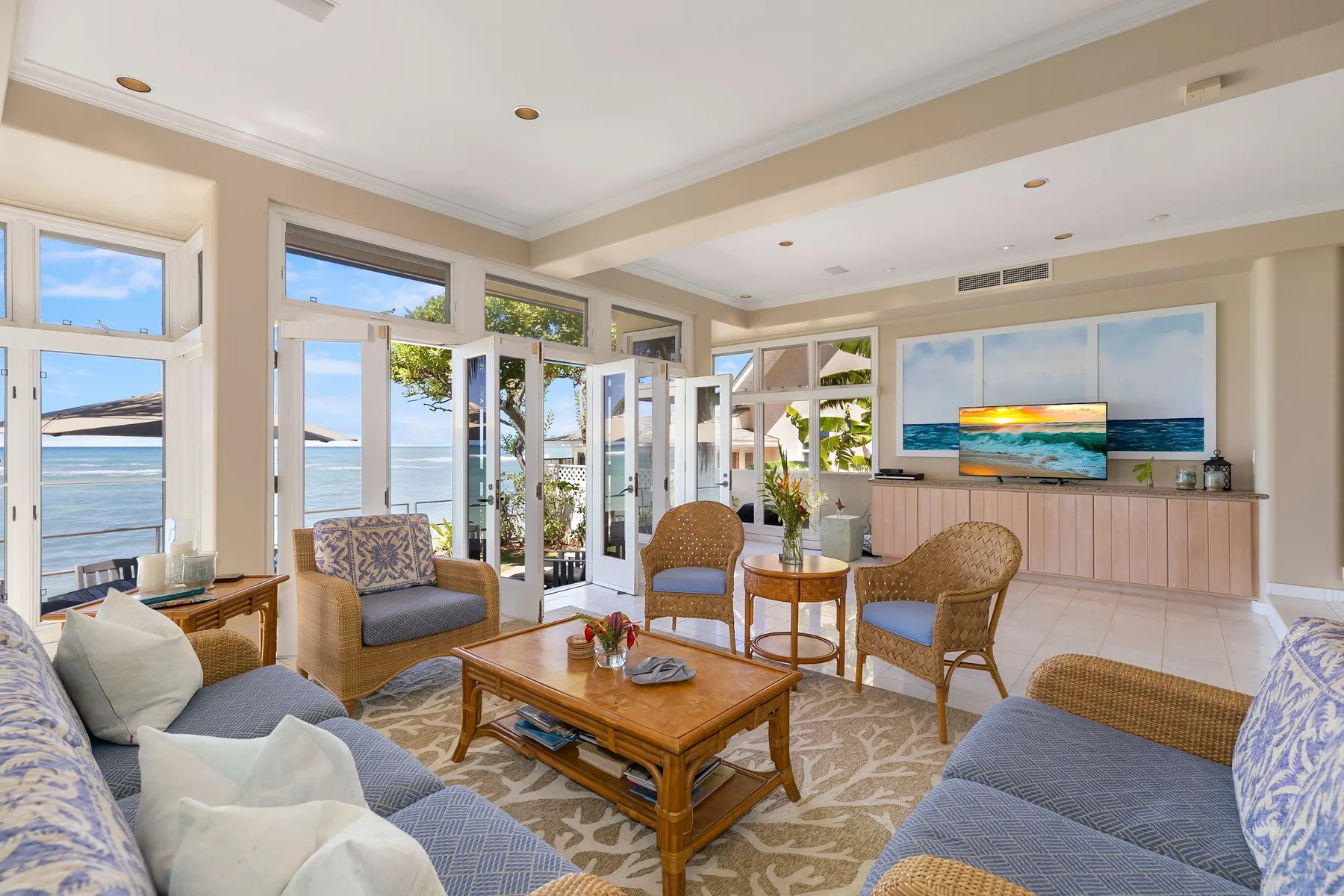A bright living room opens onto a waterfront view through large windows.