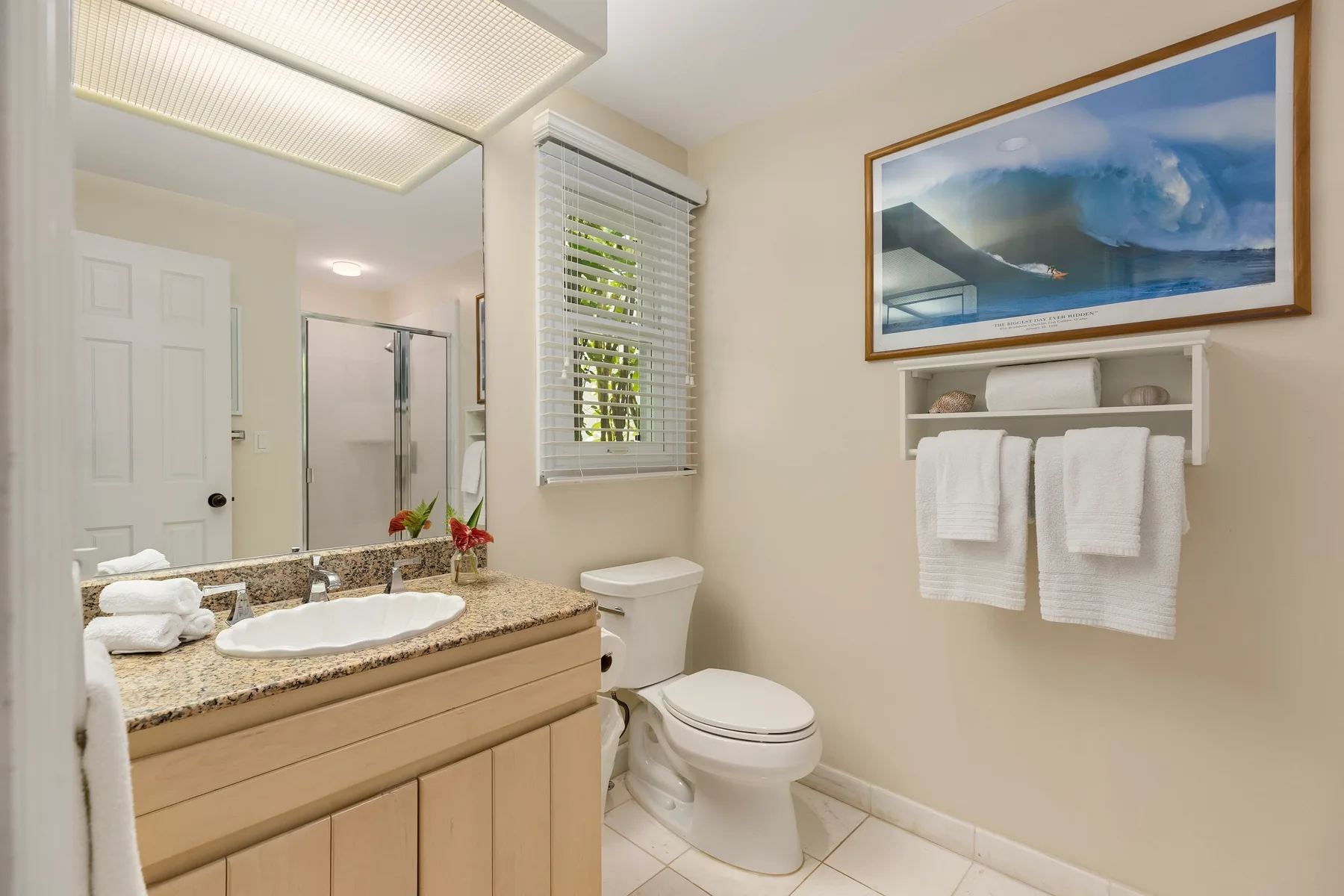 A bathroom with a vanity, toilet, and framed landscape picture.
