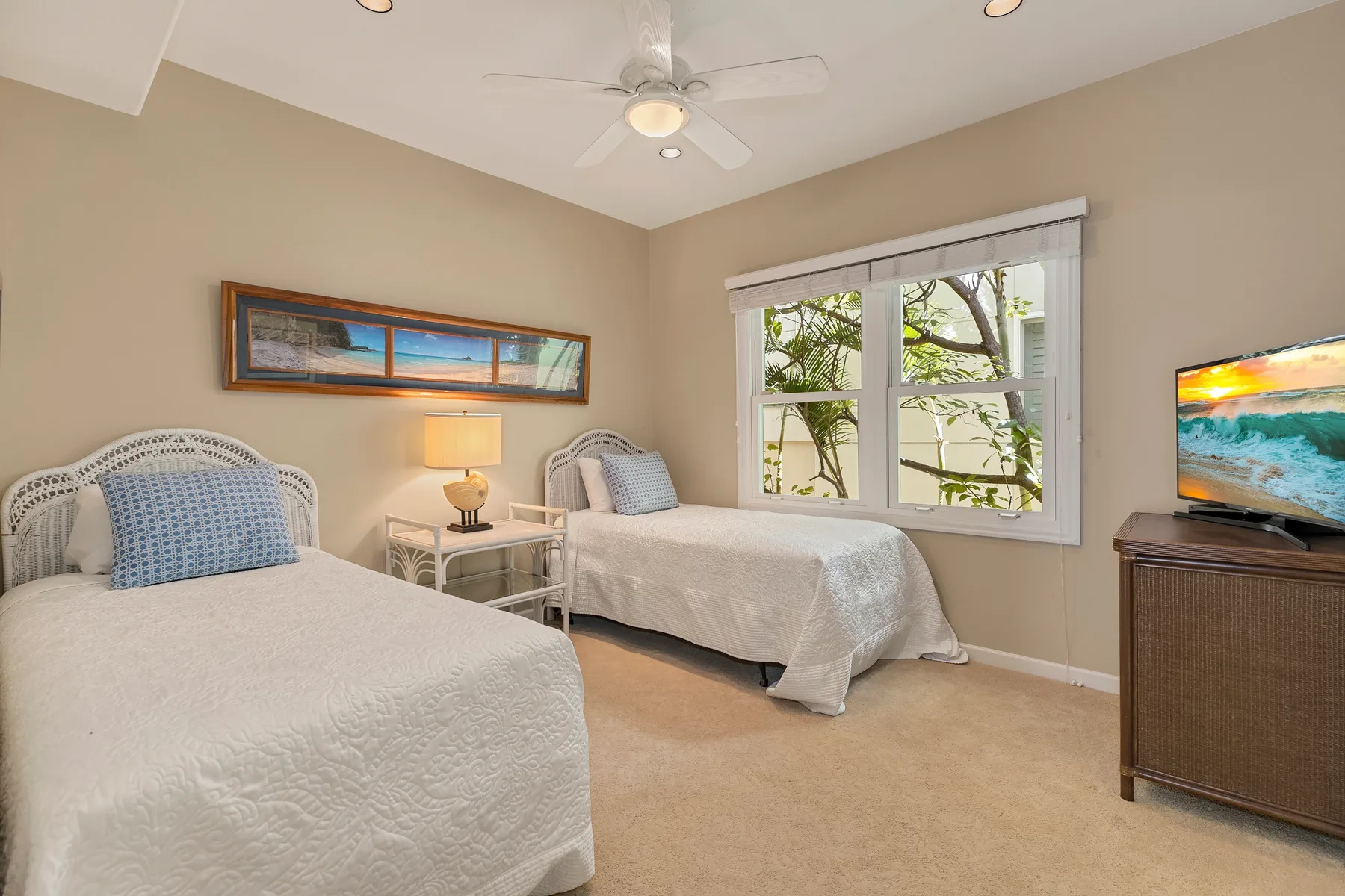 A bedroom with two beds, a window, and a television on a cabinet.