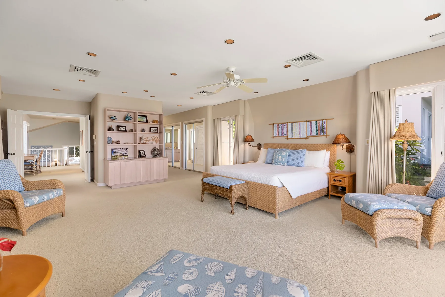 A spacious bedroom with a bed, wicker seating, and a built-in display shelf.