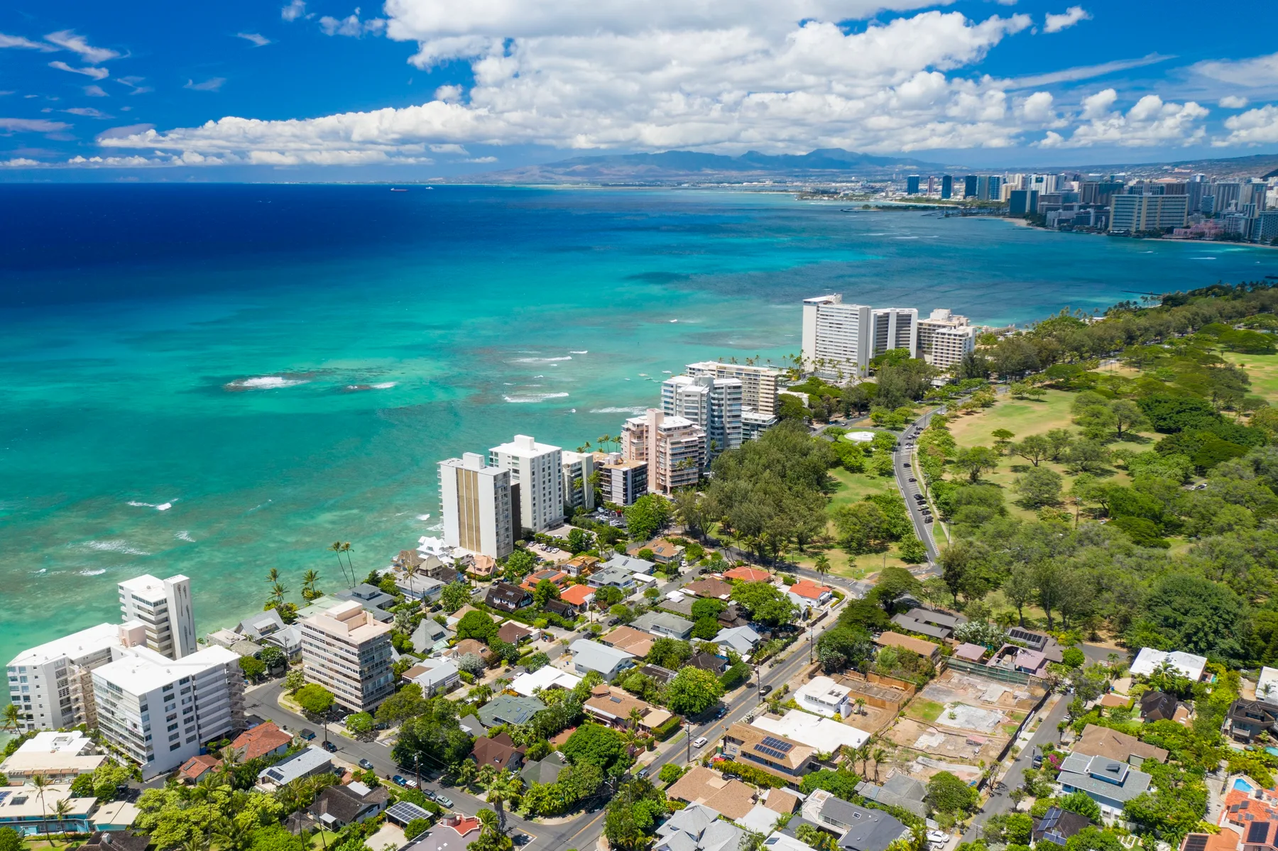 Aerial view of a coastal city with turquoise water and buildings along the shore.