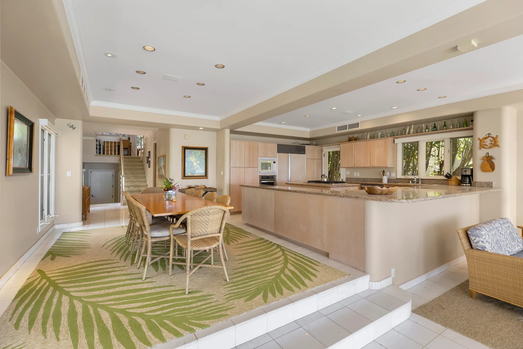 An open-plan kitchen and dining area with a patterned rug and wooden cabinetry.