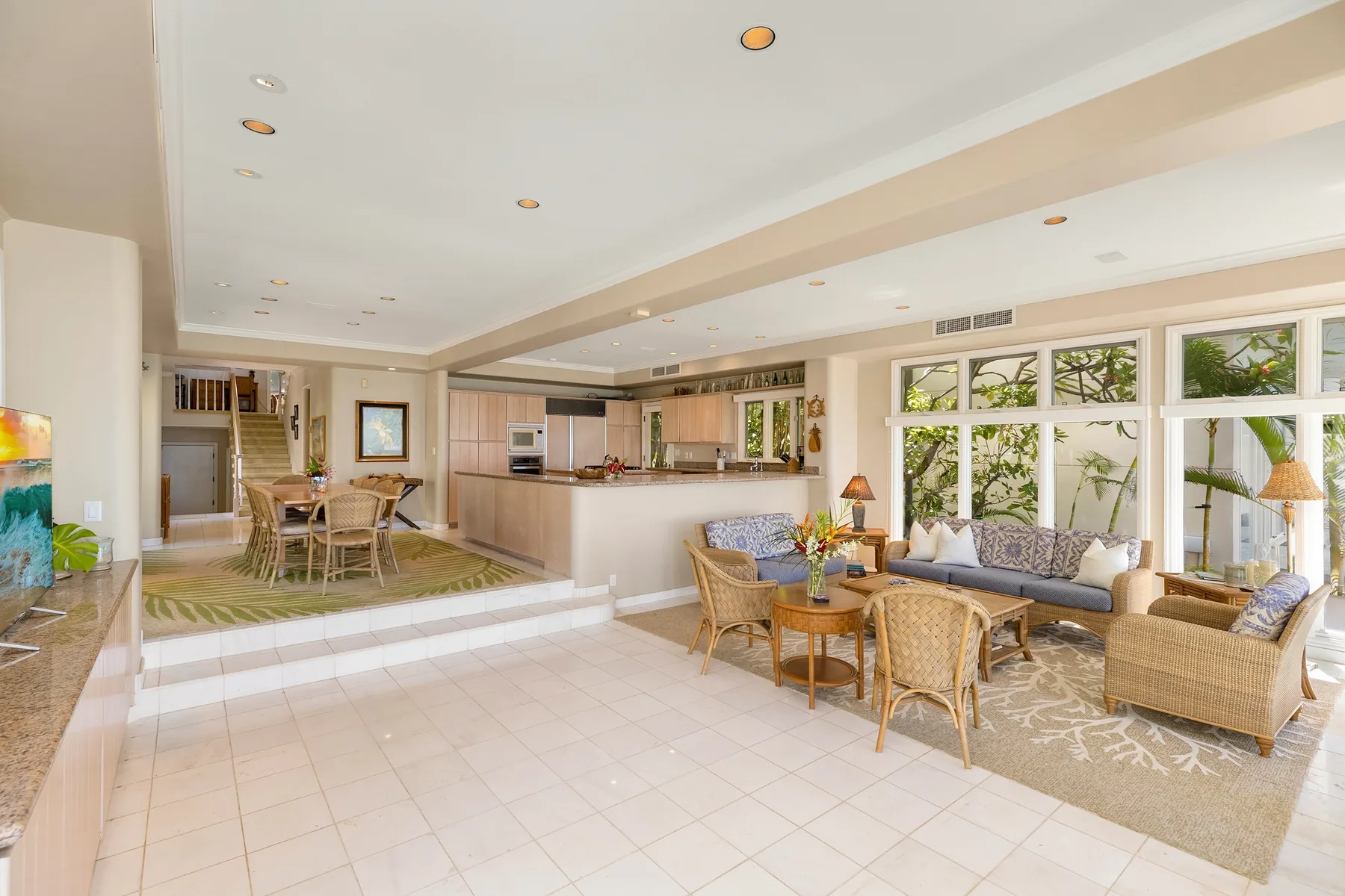 An open-plan living room and kitchen with seating beside large windows.