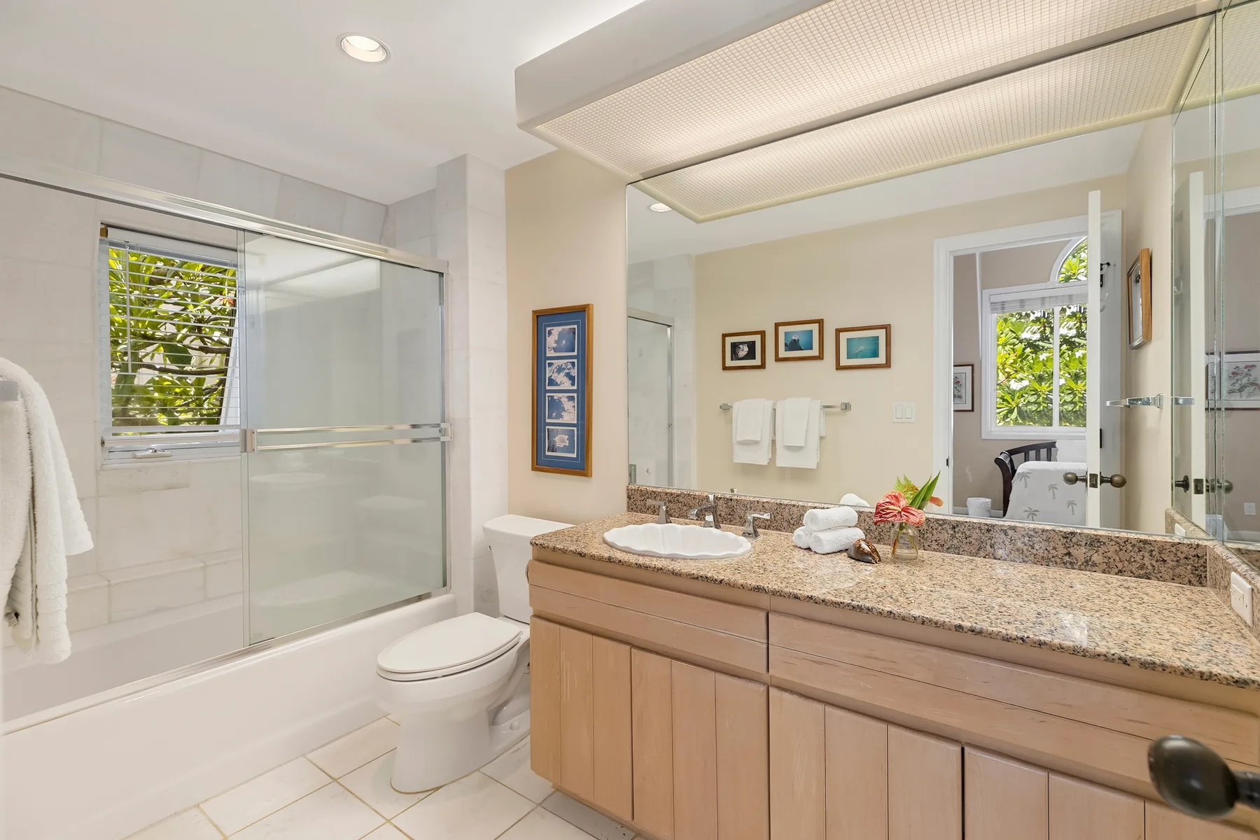 A bright bathroom with a glass shower, bathtub, and long vanity.