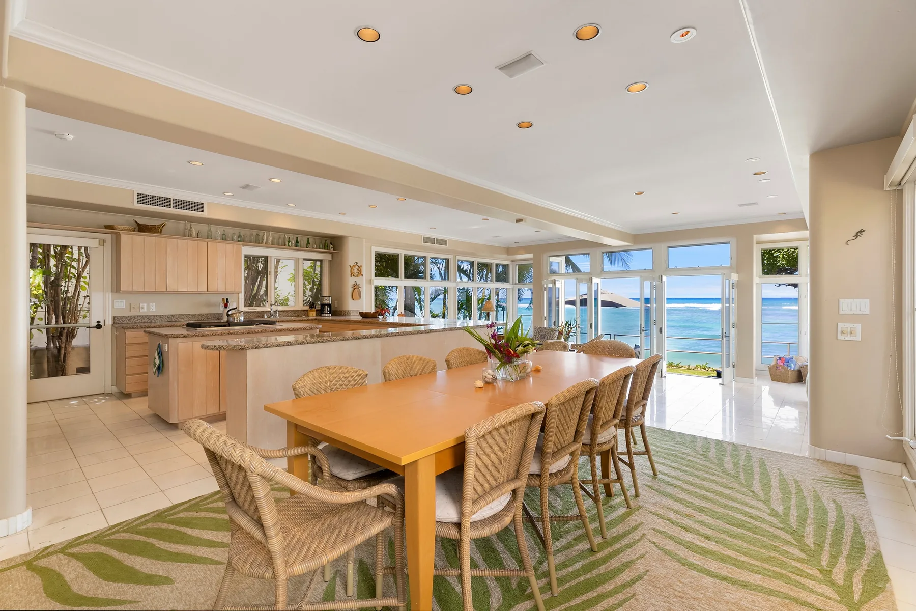 A dining area and kitchen open toward large windows overlooking the water.