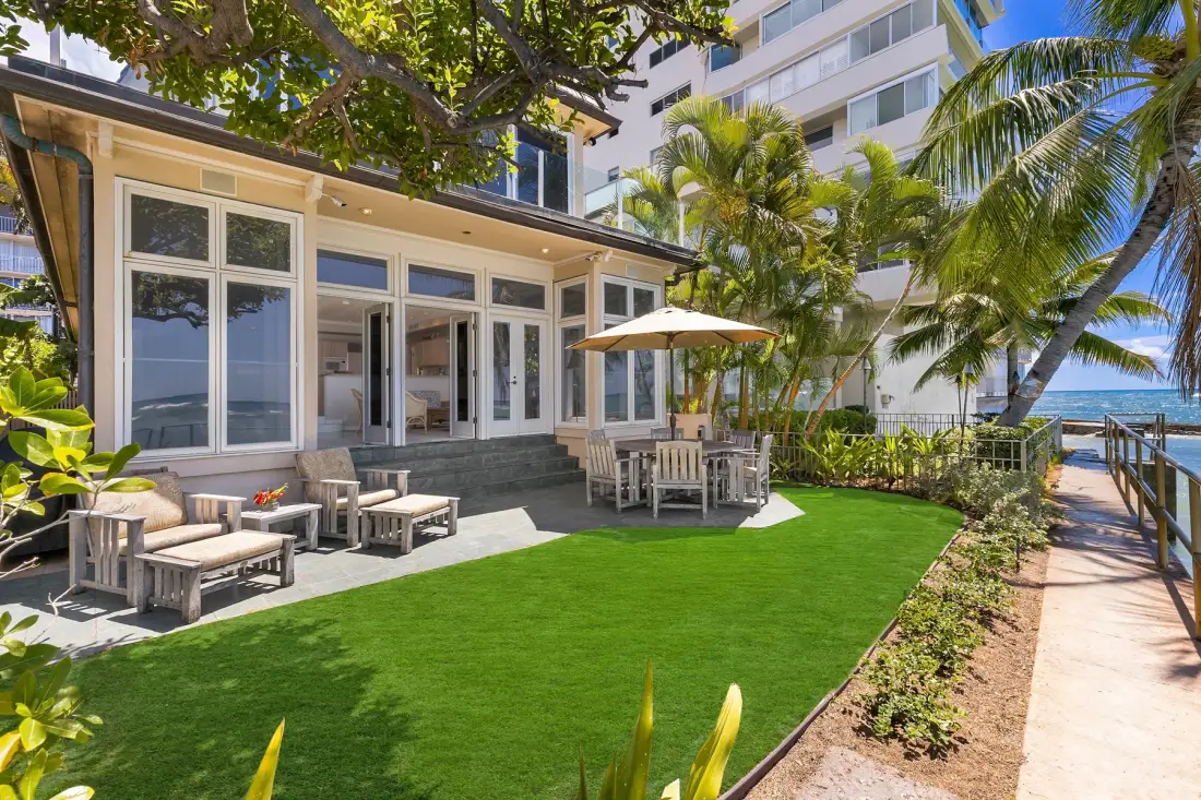 A landscaped lawn and outdoor seating area beside a glass-fronted building.