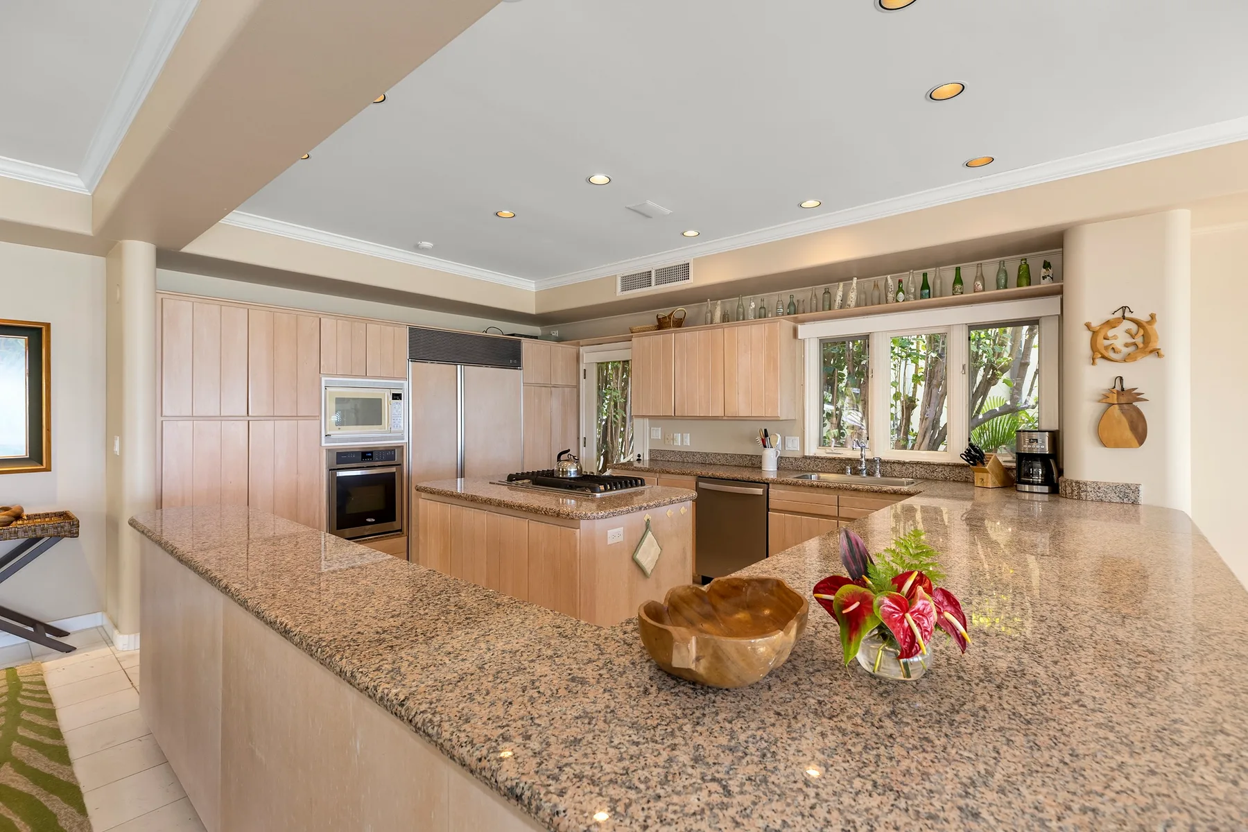 A spacious kitchen with wood cabinetry, a central island, and a large window.
