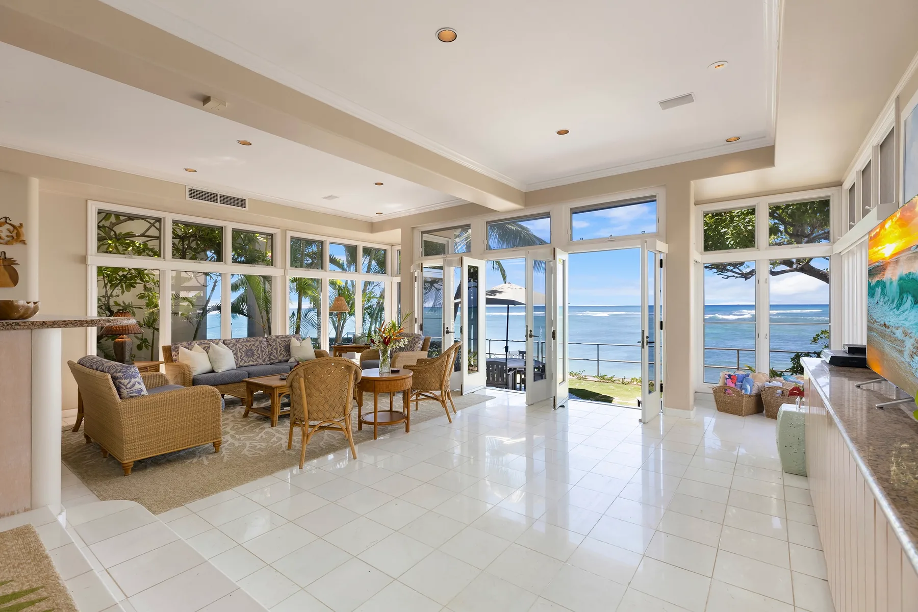 A bright living and dining area opens onto a patio overlooking the ocean.