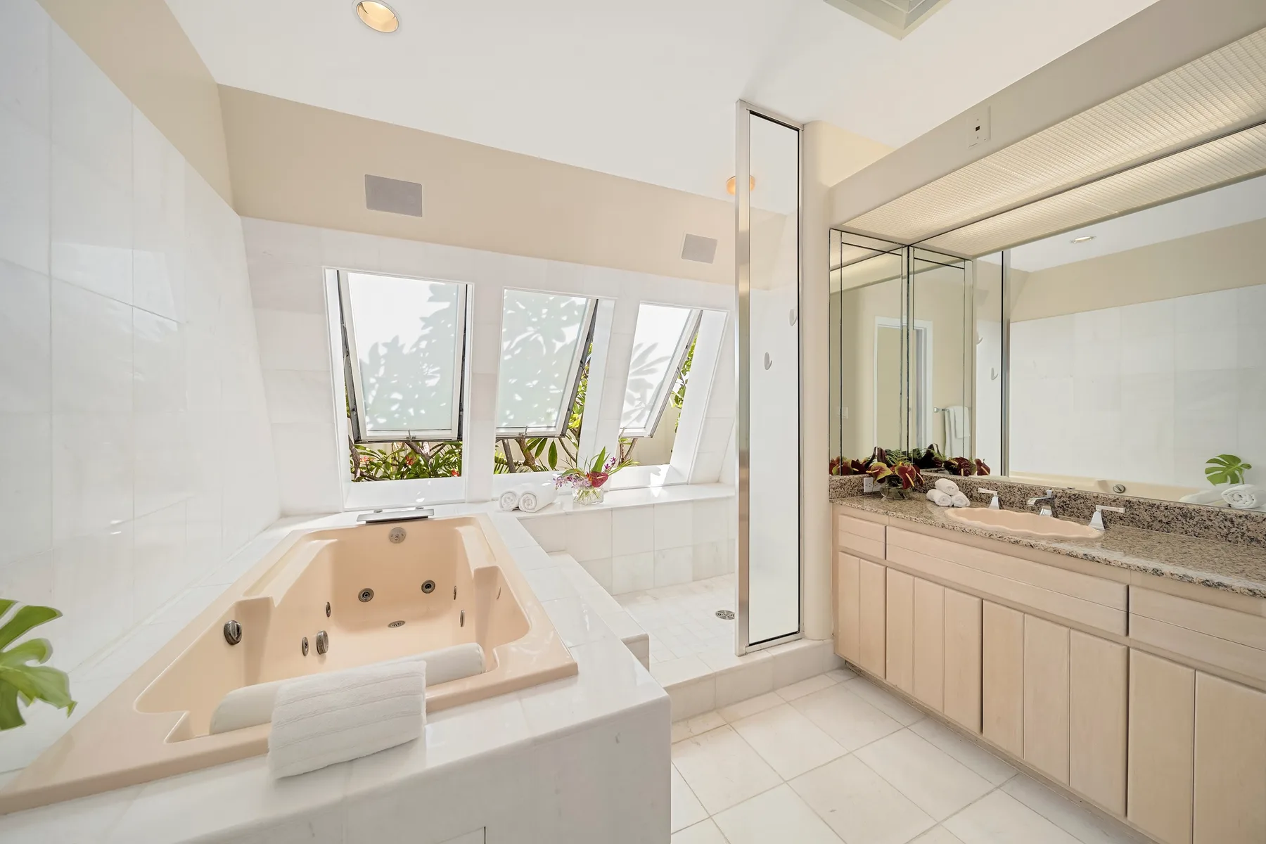 A bright bathroom with a large soaking tub and a long vanity.