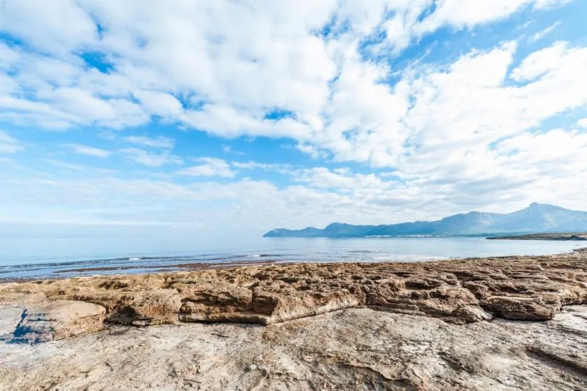 Una costa rocosa se encuentra con aguas tranquilas bajo un cielo cubierto de nubes.