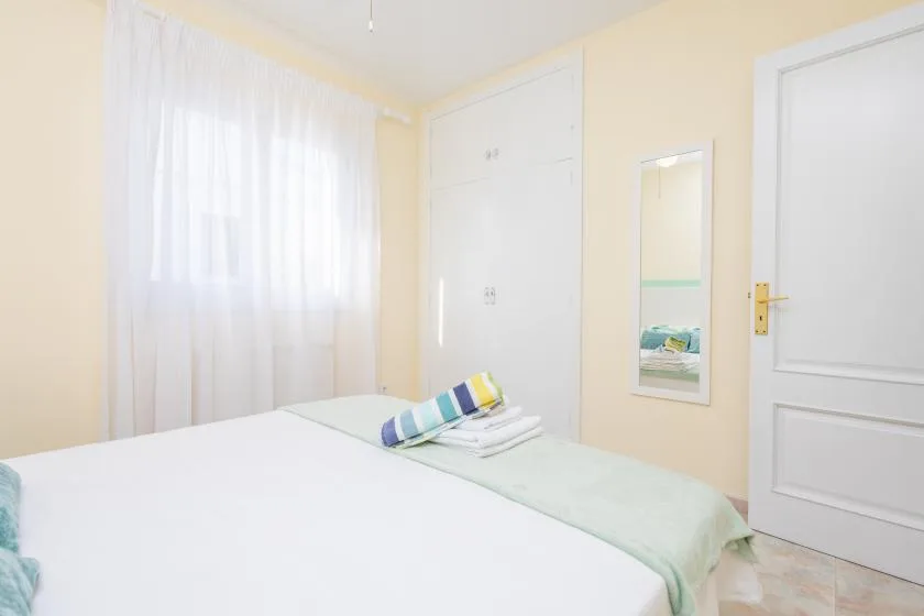 Un dormitorio luminoso con una cama junto a una gran ventana con cortinas.
