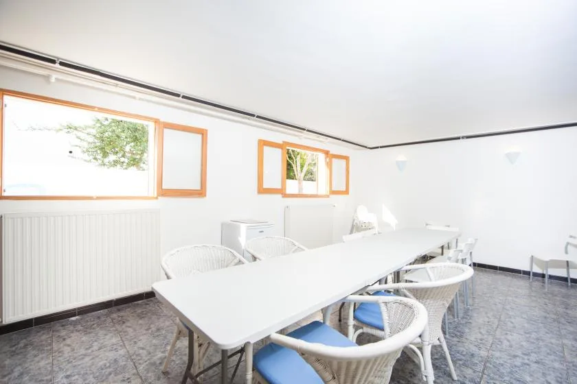 Una sala de reuniones luminosa tiene una mesa larga rodeada de sillas.