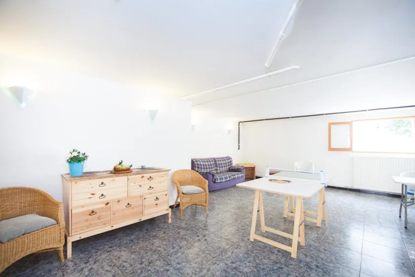 Una sala luminosa con una mesa, asientos y una cómoda de madera.