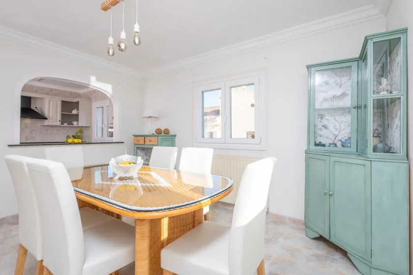 Un comedor luminoso con una mesa de madera y asientos blancos.