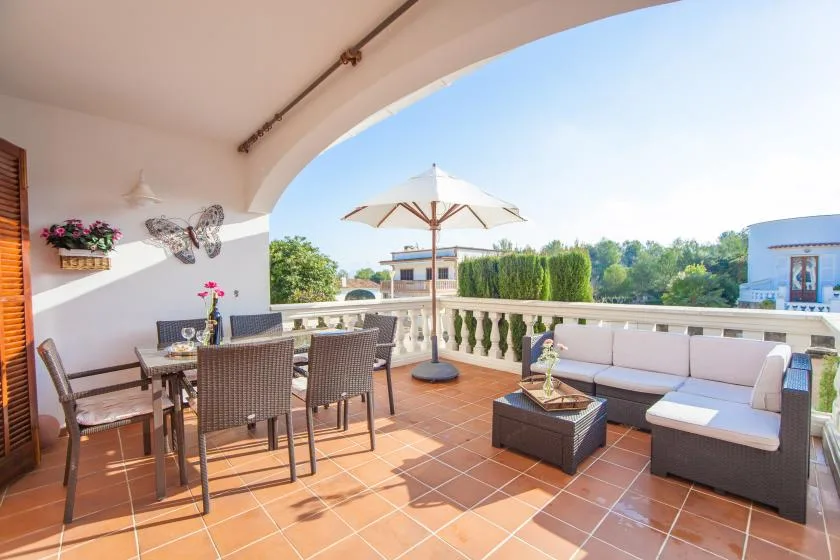 Una terraza exterior cubierta con asientos para comer y descansar y una sombrilla.