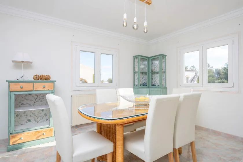 Un comedor luminoso con una mesa de vidrio y asientos tapizados claros.