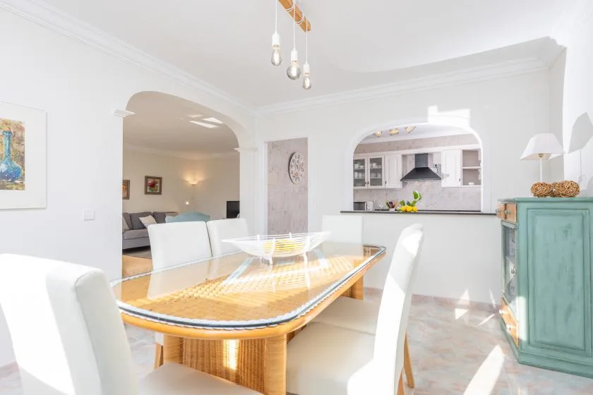 Un comedor luminoso con una mesa larga, abierto a la cocina y la sala de estar.
