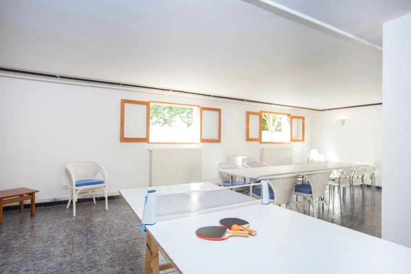 Una luminosa sala recreativa con una mesa de ping-pong y asientos.