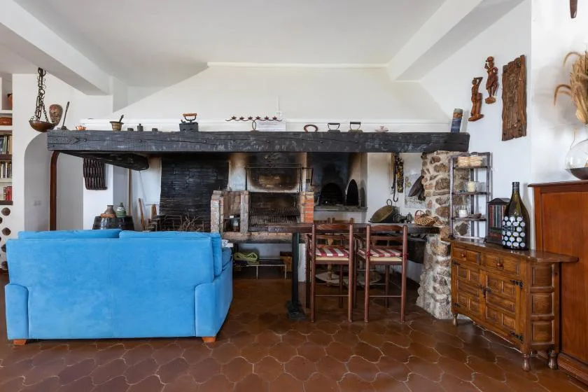 A rustic kitchen and dining area with a large fireplace and wooden table.