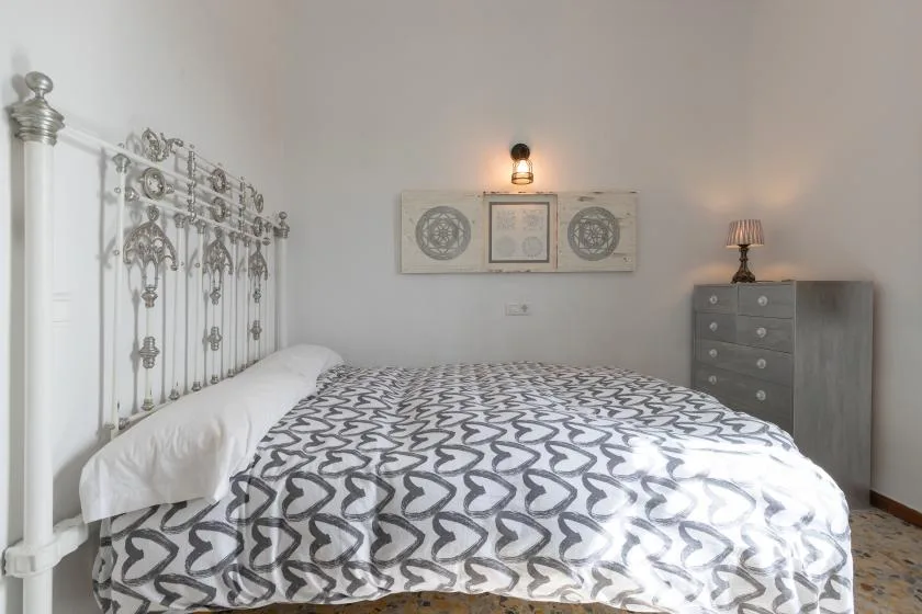A bedroom with a patterned bedspread, ornate metal headboard, and dresser.