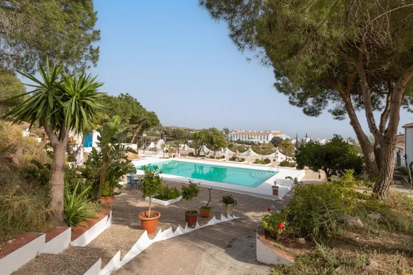 A swimming pool sits among landscaped grounds and trees.