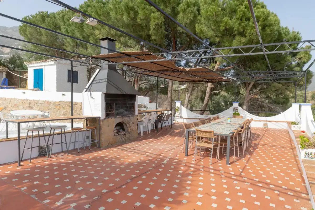 An outdoor dining terrace with tables, chairs, and a built-in grill.