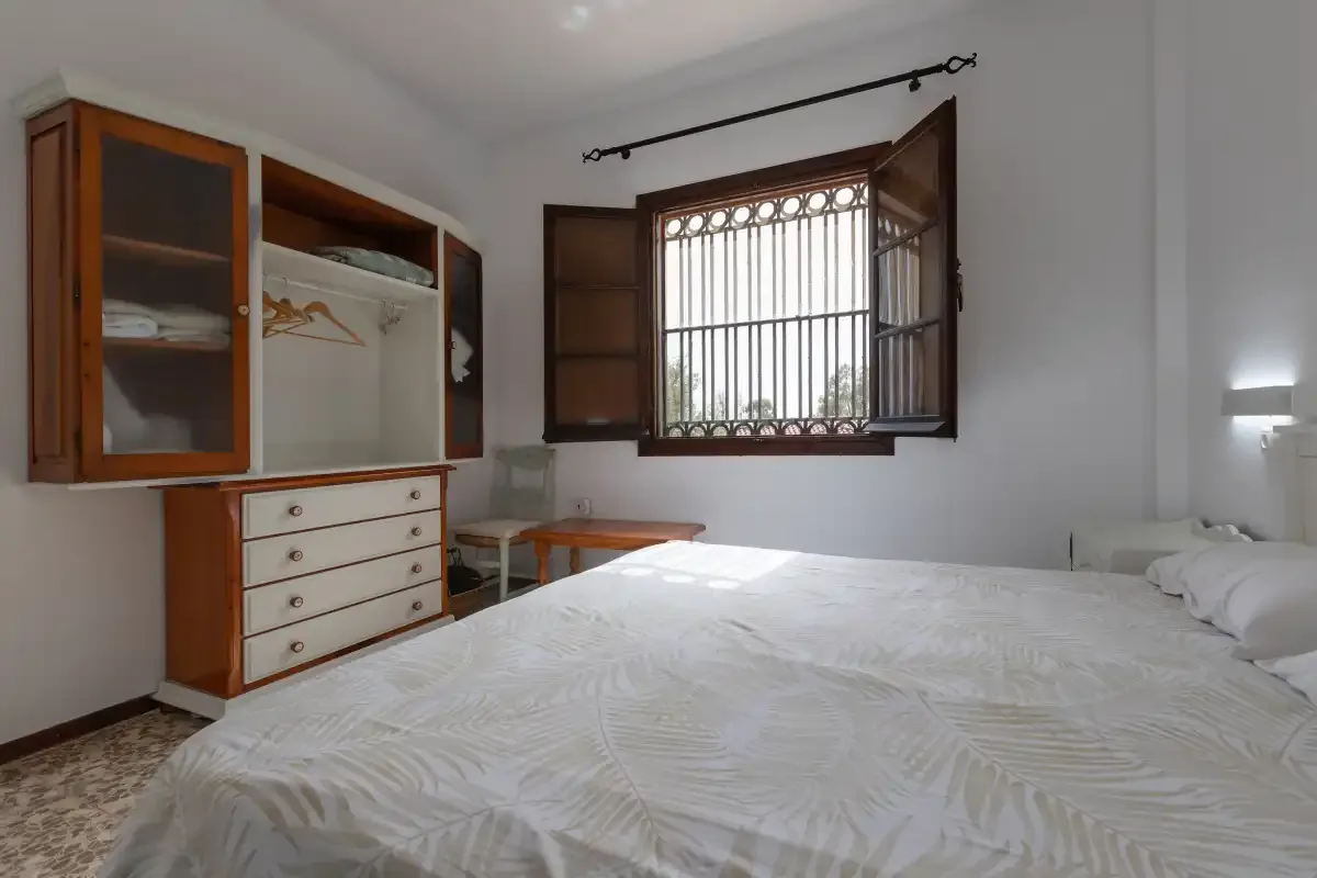 A bedroom with a bed and an open window.
