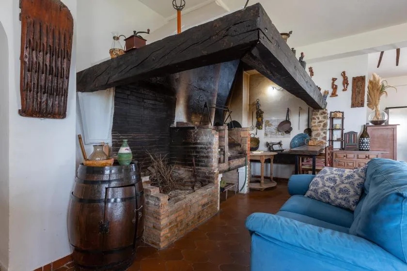 A rustic living area features a large fireplace and blue seating.