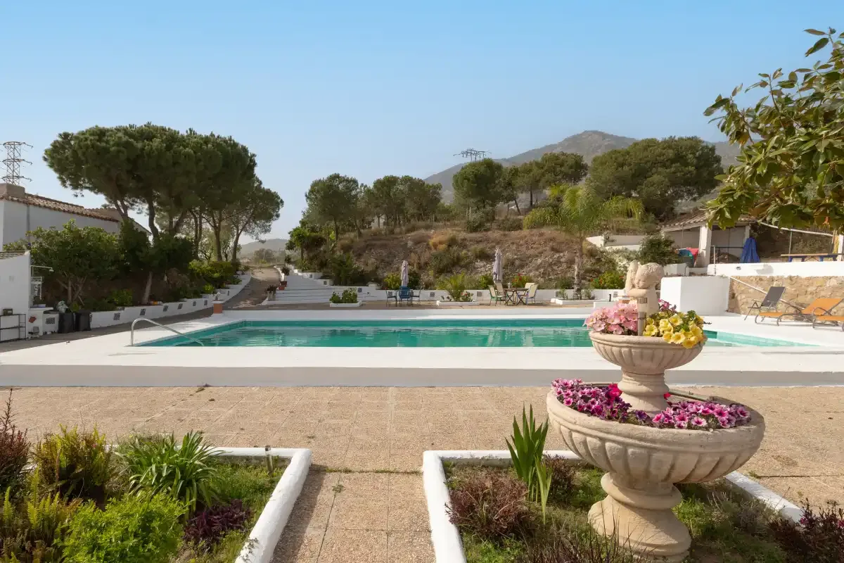 An outdoor swimming pool with landscaped gardens and a flower-filled fountain.