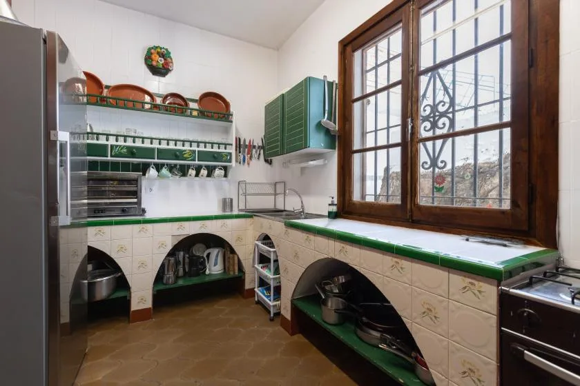 A tiled kitchen with green countertops, open shelving, and a large window.