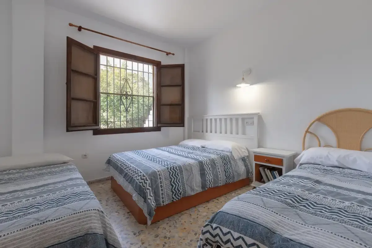 A bright bedroom with patterned bedding and an open window.