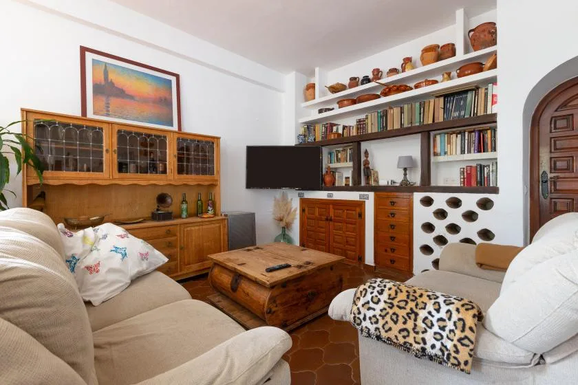 A living room with cushioned seating, a wooden coffee table, and bookshelves.