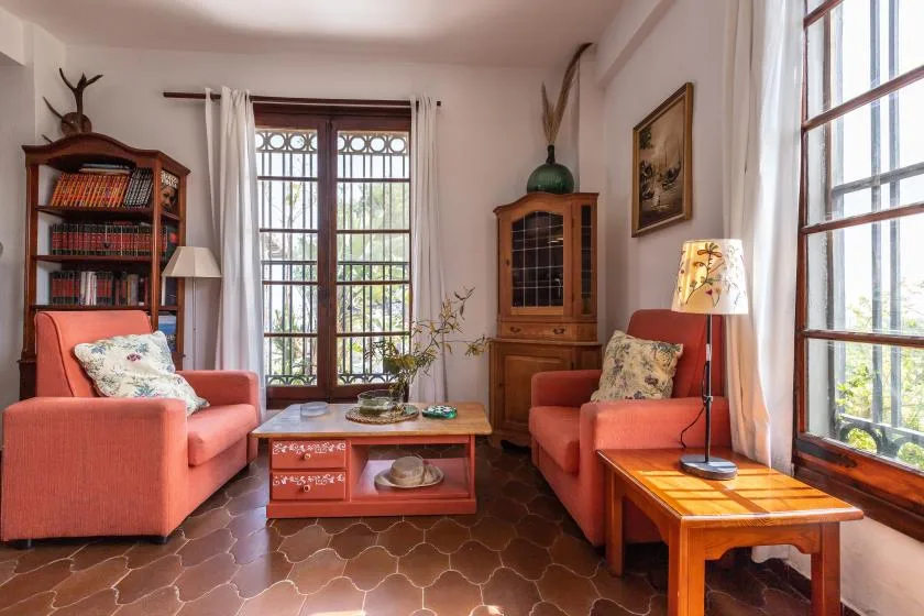 A sitting room with coral seating, a wooden coffee table, and tall windows.