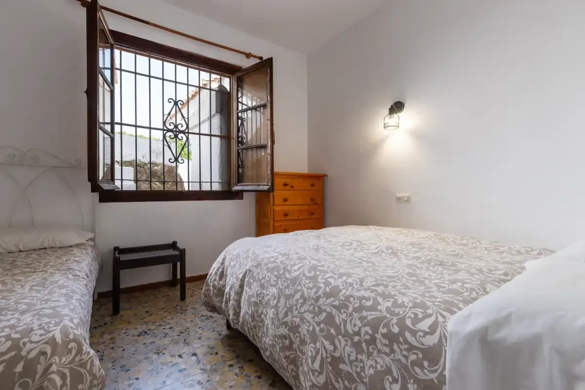 A bedroom with two beds and a barred window.