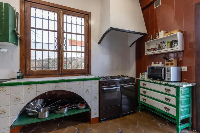 A kitchen with a stove beneath a curved hood and a window above the counter.