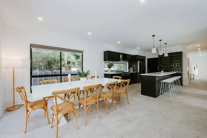 An open-plan kitchen and dining area with a long table beside large windows.