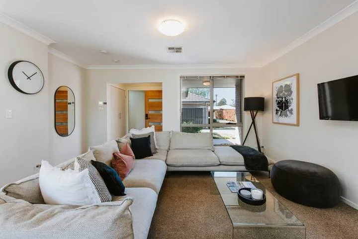 A bright living room with a sectional sofa, coffee table, and large windows.