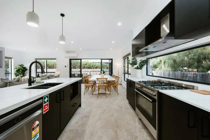 A bright open kitchen with a dining table and windows overlooking greenery.