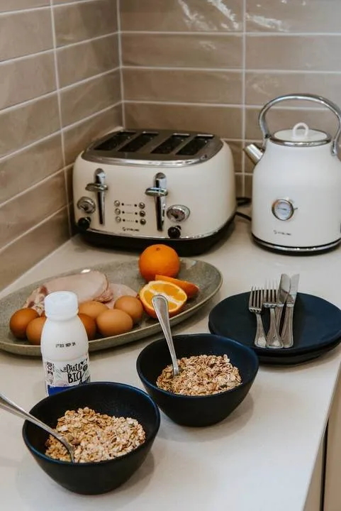 A kitchen counter with breakfast bowls, fruit, eggs, and small appliances.
