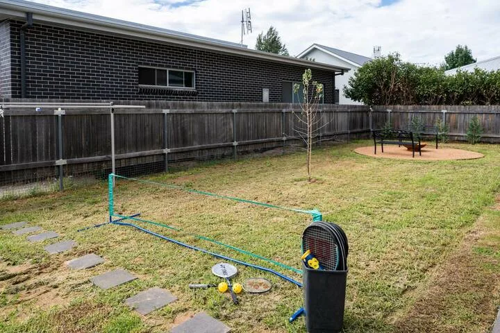 A fenced backyard with a lawn and a small play area.