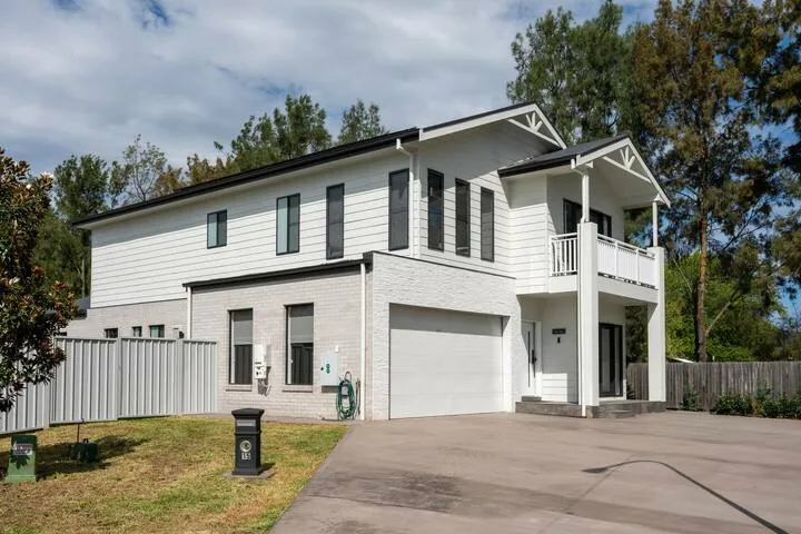 A two-story white house with a garage, driveway, and upper balcony.
