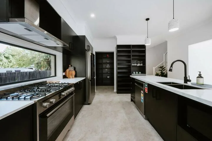 A modern kitchen with dark cabinetry, a gas cooktop, and a long central island.